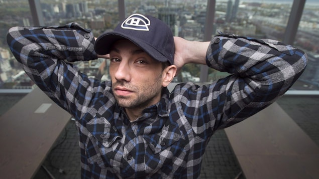 Jay Baruchel posant devant une vitre à l'intérieur d'un gratte-ciel. Il porte une casquette à l'effigie des Canadiens de Montréal.