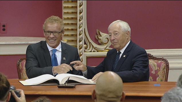 Jean Boulet qui finit de signer un document aux côtés du lieutenant-gouverneur, à Québec Jean Boulet qui finit de signer un document aux côtés du lieutenant-gouverneur, à Québec
