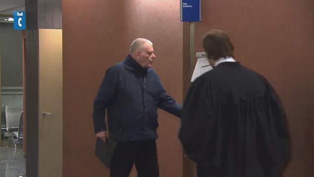 Jean-Claude Rochefort tient une porte dans un couloir du palais de justice de Montréal.