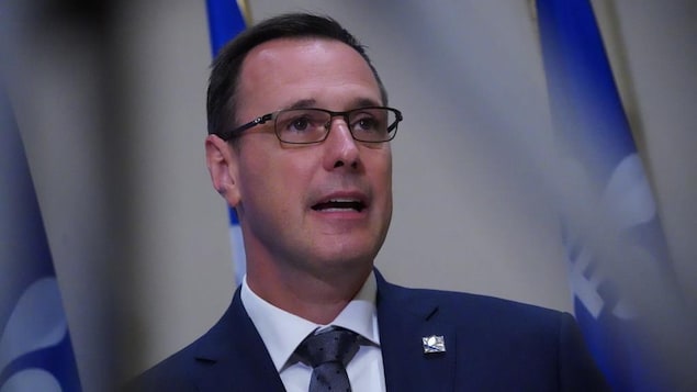 M. Roberge devant un drapeau du Québec.