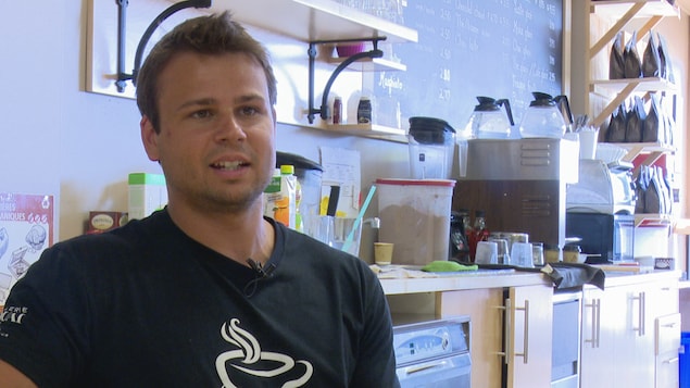 Un homme est assis derrière le comptoir d'un café. Il s'agit du propriétaire d'un café. Un homme est assis derrière le comptoir d'un café. Il s'agit du propriétaire d'un café.