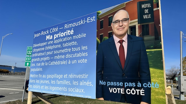 Une pancarte électorale montre le candidat Jean-Rock Côté devant une image d'hôtel de ville générée par l'intelligence artificielle.
