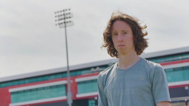Il pose avec le stade Telus derrière lui.