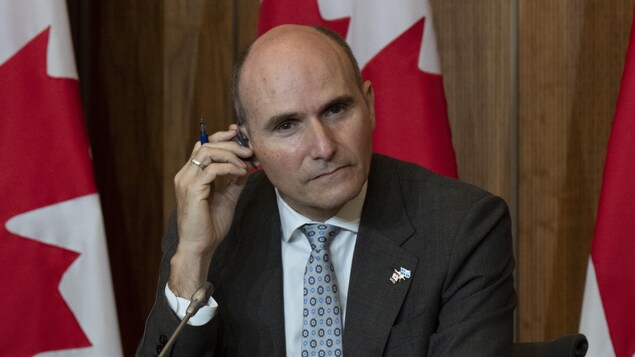 Jean-Yves Duclos ajuste son oreillette pendant une conférence de presse.