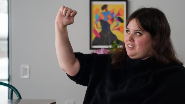 Jeanne Carrière, 27, of Lachute, Que., holds her hand in a fist, something she wasn't able to do after breaking her neck in 2021 and losing use of her hands and lower body. But thanks to surgery at Montreal's Maisonneuve-Rosemont Hospital in July 2022, function is returning. (Esteban Cuevas/CBC )