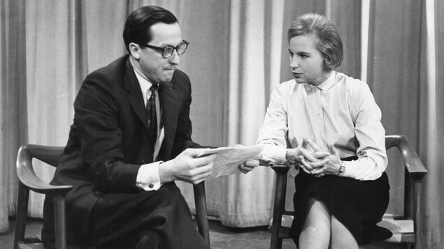 Le Dr Lazure et Jeanne Sauvé en discussion, assis sur des chaises de bois Le Dr Lazure et Jeanne Sauvé en discussion, assis sur des chaises de bois