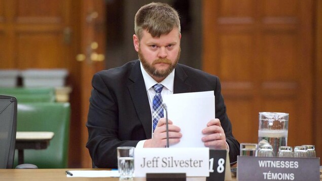 Jeff Silvester est assis à un bureau avec des feuilles dans les mains.