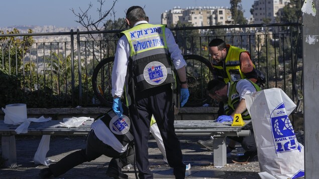 Des gens nettoient le sang de la scène d'une explosion à un arrêt de bus à Jérusalem.