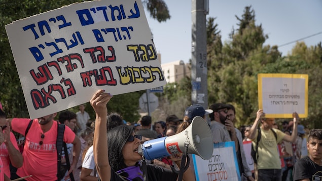 Des Israéliens avec pancarte et porte-voix.