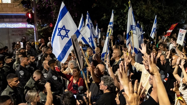 Des personnes manifestent avec des drapeaux israéliens.