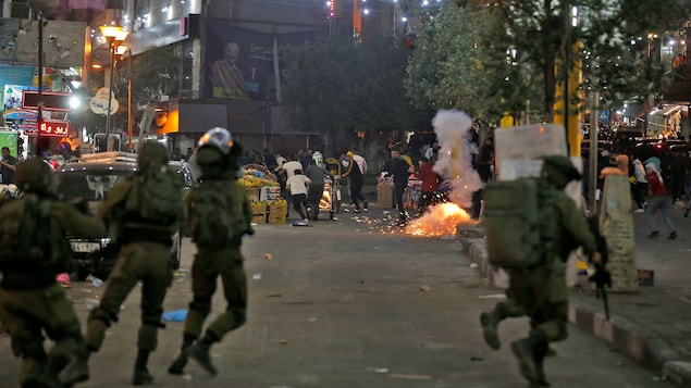 Palestinos se enfrentan a las fuerzas de seguridad israelíes en el centro de la ciudad cisjordana de Hebrón, el 12 de mayo de 2021. - Las hostilidades más intensas en siete años entre Israel y los grupos armados de Gaza se desencadenaron por los disturbios del fin de semana en el recinto de la mezquita de Al-Aqsa de Jerusalén, que es sagrada tanto para los musulmanes como para los judíos.