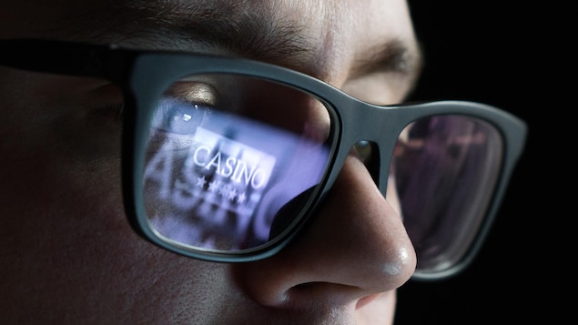 Reflet d'une image de casino virtuel dans les lunettes d'un homme.