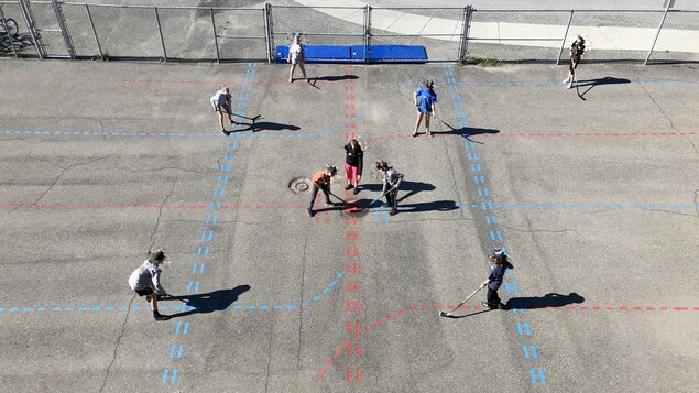 Plan aérien de jeunes qui pratiquent le hockey-balle dans une cour d'école.