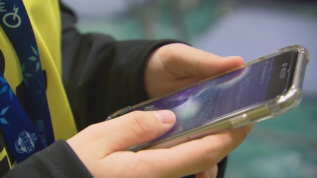 Une jeune tient un cellulaire dans ses mains