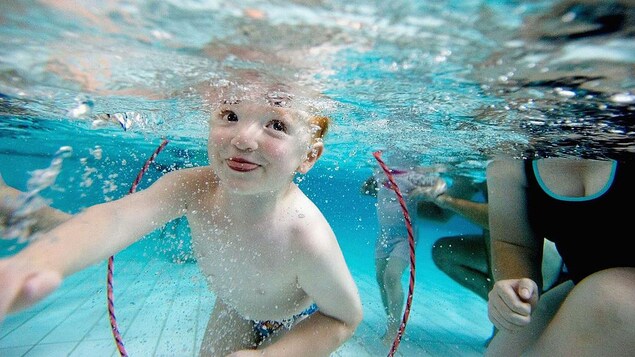 Un petit garçon joue dans une piscine avec sa mère lors d'un cours de natation.