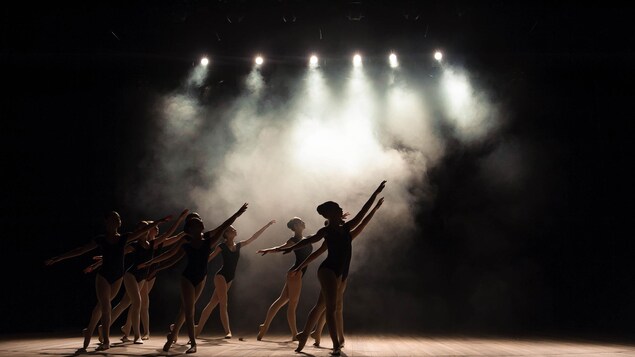 Des jeunes pratiquent le ballet sur une scène enfumée.