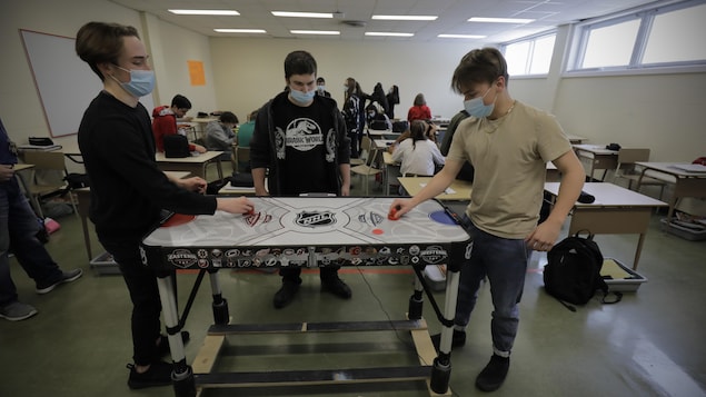 Des élèves jouent au hockey sur table dans leur classe.