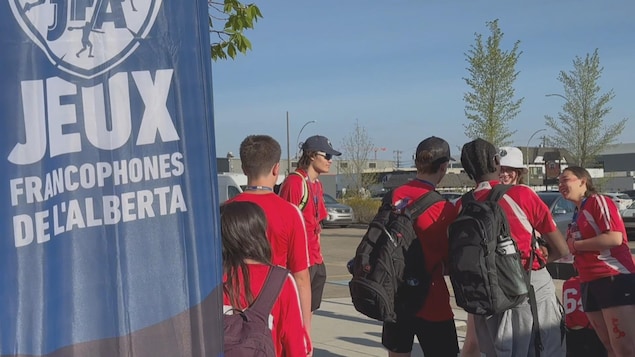 Des participants des Jeux francophones de l'Alberta devant une bannière des jeux.
