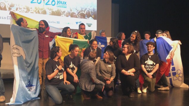 Les jeunes organisateurs des Jeux FC montrent les drapeaux de leurs provinces et territoires sur la scène du théâtre de l'école Victor Brodeur.