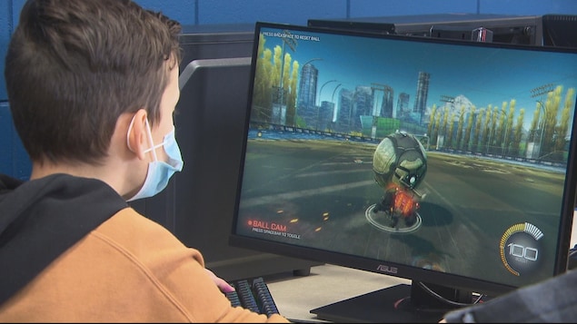 Un jeune portant un masque joue à Rocket League.