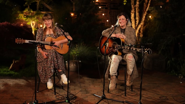 Jill Barber et Maïa Davies assises à l'extérieur le soir, avec leurs guitares.