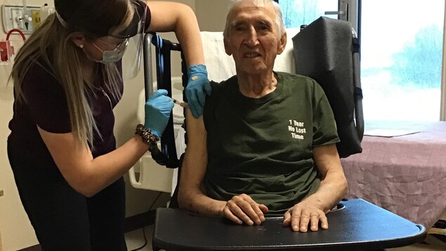 Une infirmière injecte une dose du vaccin Moderna dans le bras droit de Jimmy Favel.