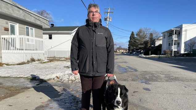 Jimmy Turgeon-Carrier se promène dans la rue avec son chien. Des plaques de glace se trouvent au sol.