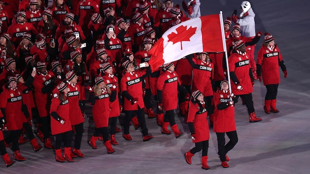 Tessa Virtue et Scott Moir portent le drapeau canadien.