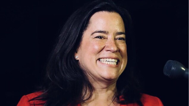 Une femme dans la quarantaine vue de face est tout sourire.