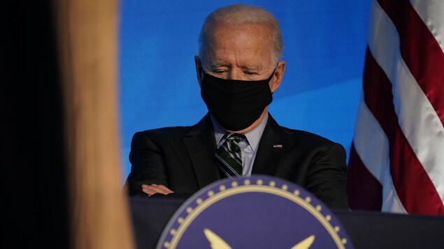 Joe Biden est derrière un lutrin, près d'un drapeau des États-Unis.