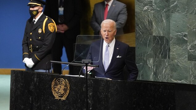 Joe Biden parle devant un lutrin aux Nations unies, près d'un garde en uniforme.