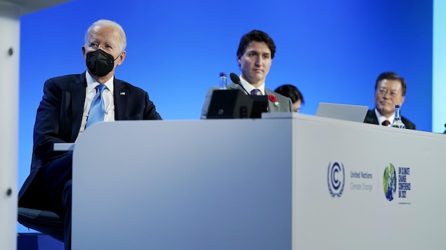 Joe Biden, Justin Trudeau et Moon Jae-in sont assis côte à côte derrière un bureau.