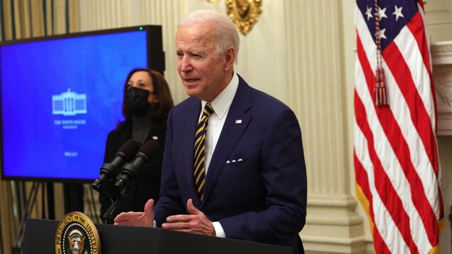 Joe Biden parle dans un micro. Derrière lui, Kamala Harris se tient debout, un masque sur le visage.
