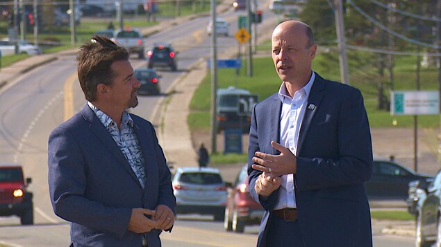 Luc Gagnon et Joël Arseneau sont debouts devant une rue de l'archipel.