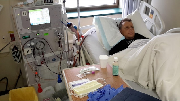 Homme couché sur un lit d'hôpital avec une machine de dialyse rénale à ses côtés.