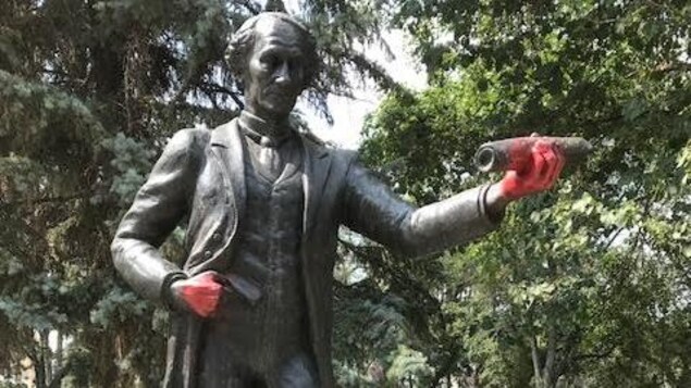 Statue de John A. Macdonald au centre-ville de Regina, dont les mains sont recouvertes de peinture rouge. Statue de John A. Macdonald au centre-ville de Regina, dont les mains sont recouvertes de peinture rouge.