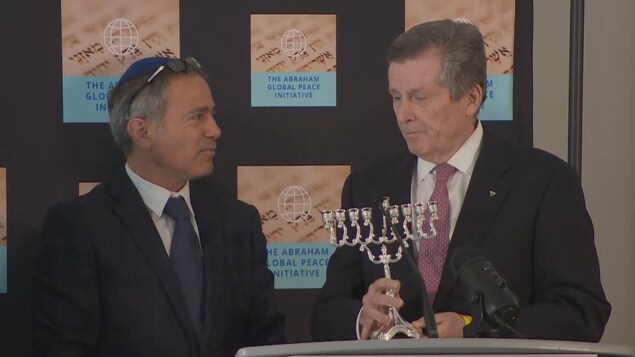 John Tory tenant un candélabre juif, symbole de la lumière, aux côtés d'Avi Benlolo.