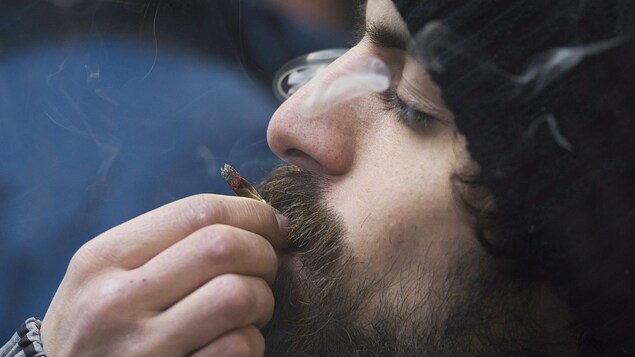 Un homme fume un joint.