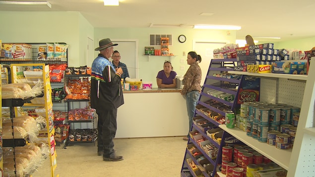 Joseph Poirier dans le magasin général de Kawacatoose avec ses tiges dans les mains et trois autres personnes Joseph Poirier dans le magasin général de Kawacatoose avec ses tiges dans les mains et trois autres personnes