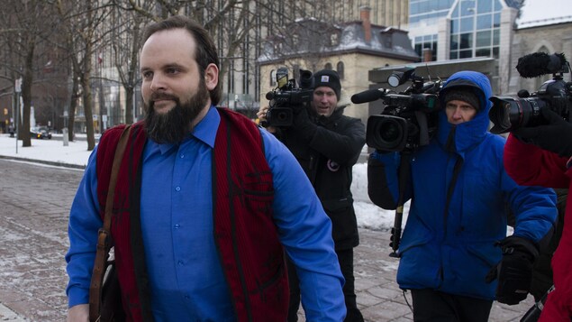 Joshua Boyle marche à l'extérieur suivi par des caméras de télévision.