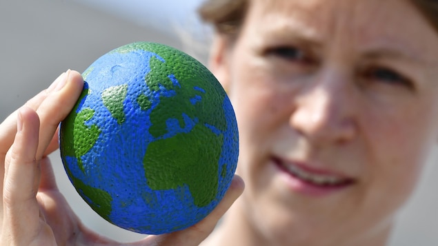 Une femme tient une boule représentant la planète dans sa main.