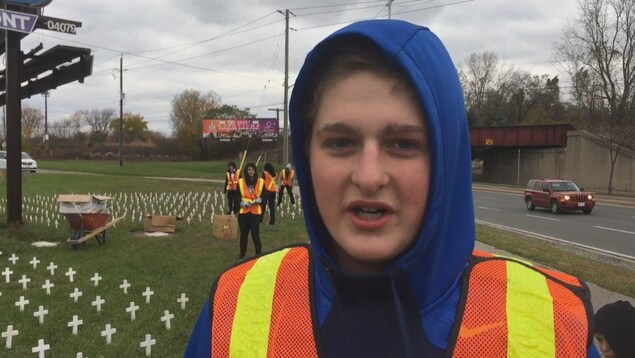 Potrait d'un jeune homme. En arrière plan d'autres jeunes gens s'activent sur un terrain le long d'une route. Potrait d'un jeune homme. En arrière plan d'autres jeunes gens s'activent sur un terrain le long d'une route.