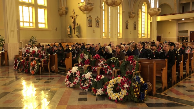 Des gerbes de fleurs sont déposées devant les bancs de l'église. Les gens sont assis derrière. Des gerbes de fleurs sont déposées devant les bancs de l'église. Les gens sont assis derrière.