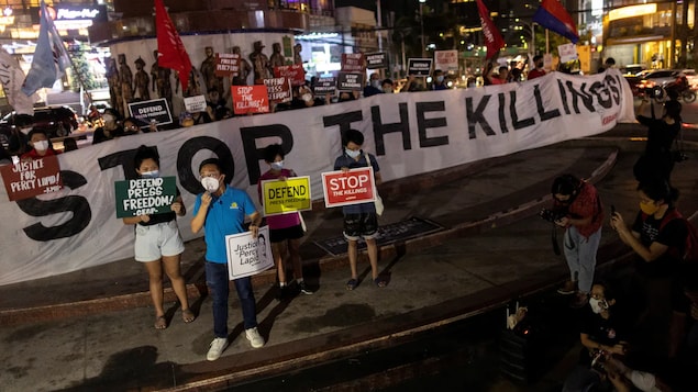 Mga nagpoprotesta sa kalsada na may hawak na banner na nagsasabing "Stop the killings."