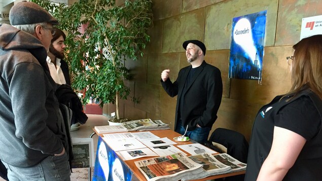 Un homme derrière un kiosque d'information discute avec des passants. Un homme derrière un kiosque d'information discute avec des passants.