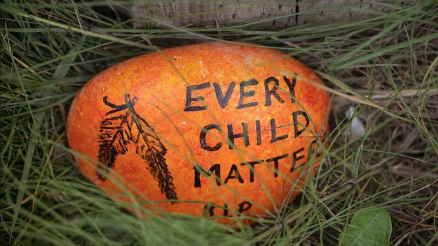 Une pierre colorée sur laquelle il est écrit : la vie de chaque enfant compte. 