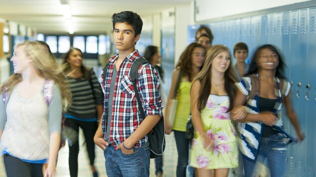 Un élève du secondaire debout dans un corridor.