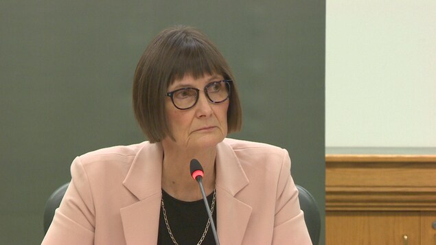 Judy Ferguson regarde sur le côté et écoute attentivement.