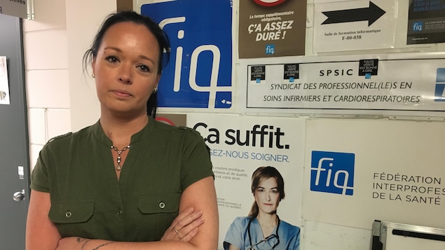 Julie Bouchard pose devant des affiches de la FIQ