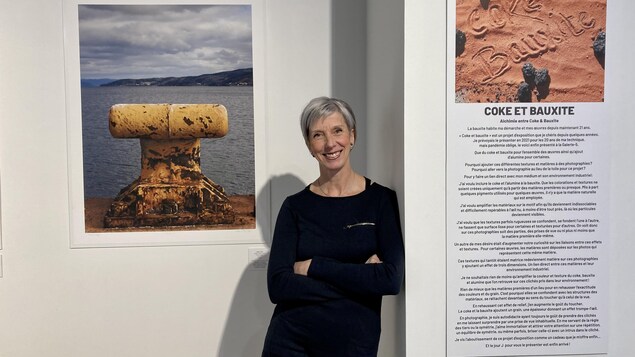 L'artiste saguenéenne Sophie Lebeuf posée devant l'une de ses oeuvres photographiques illustrant un taquet d'amarrage pour navire.